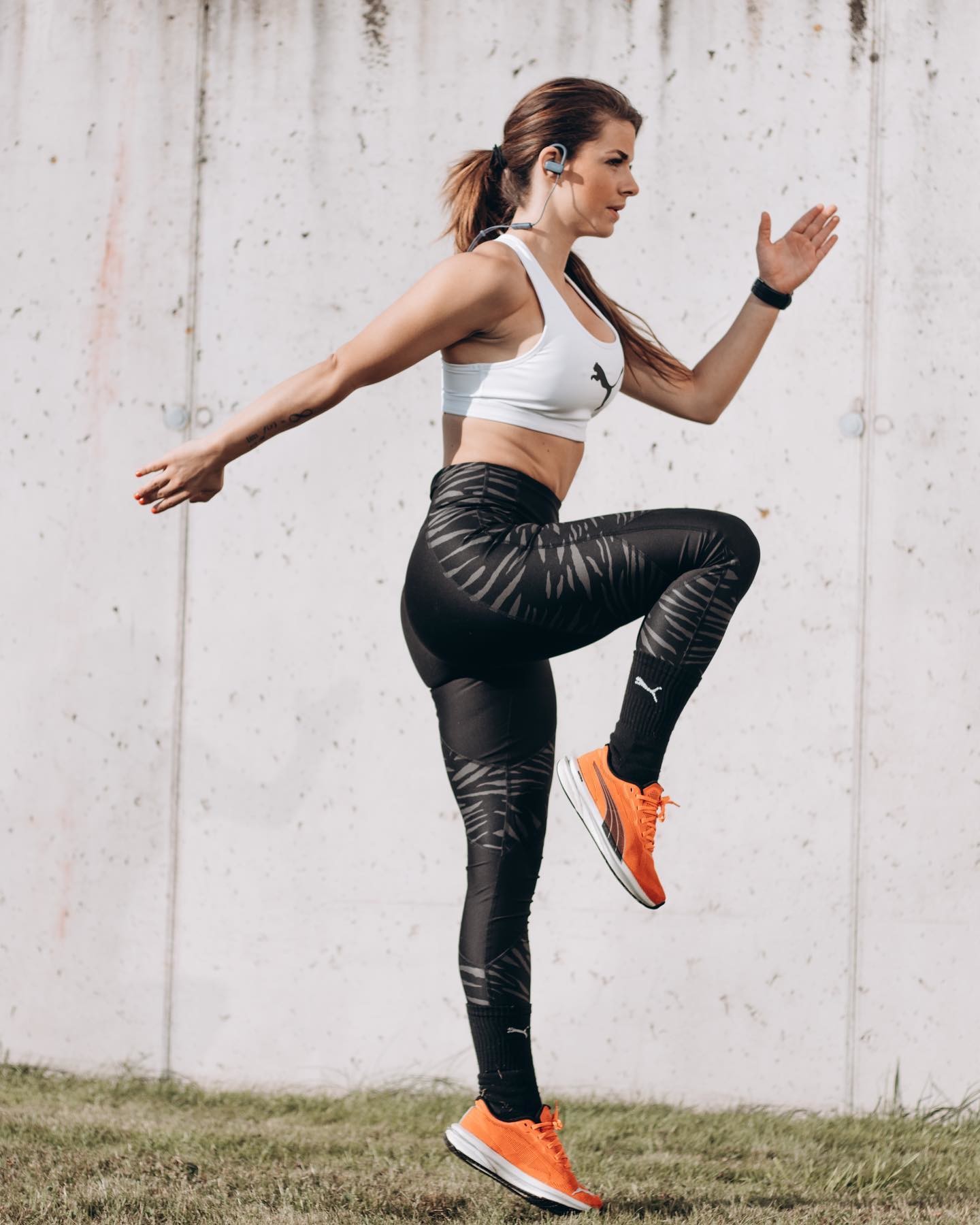 Läuferin in PUMA Yogapants und weißem PUMA Sport-BH macht High-Jumps