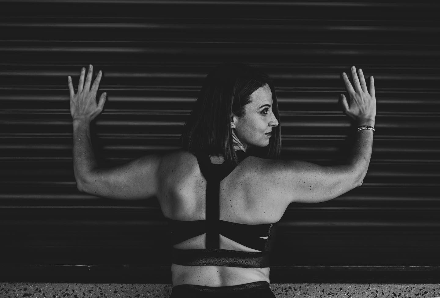 Une femme en tenue de sport PUMA pose ses mains contre un mur et regarde en arrière