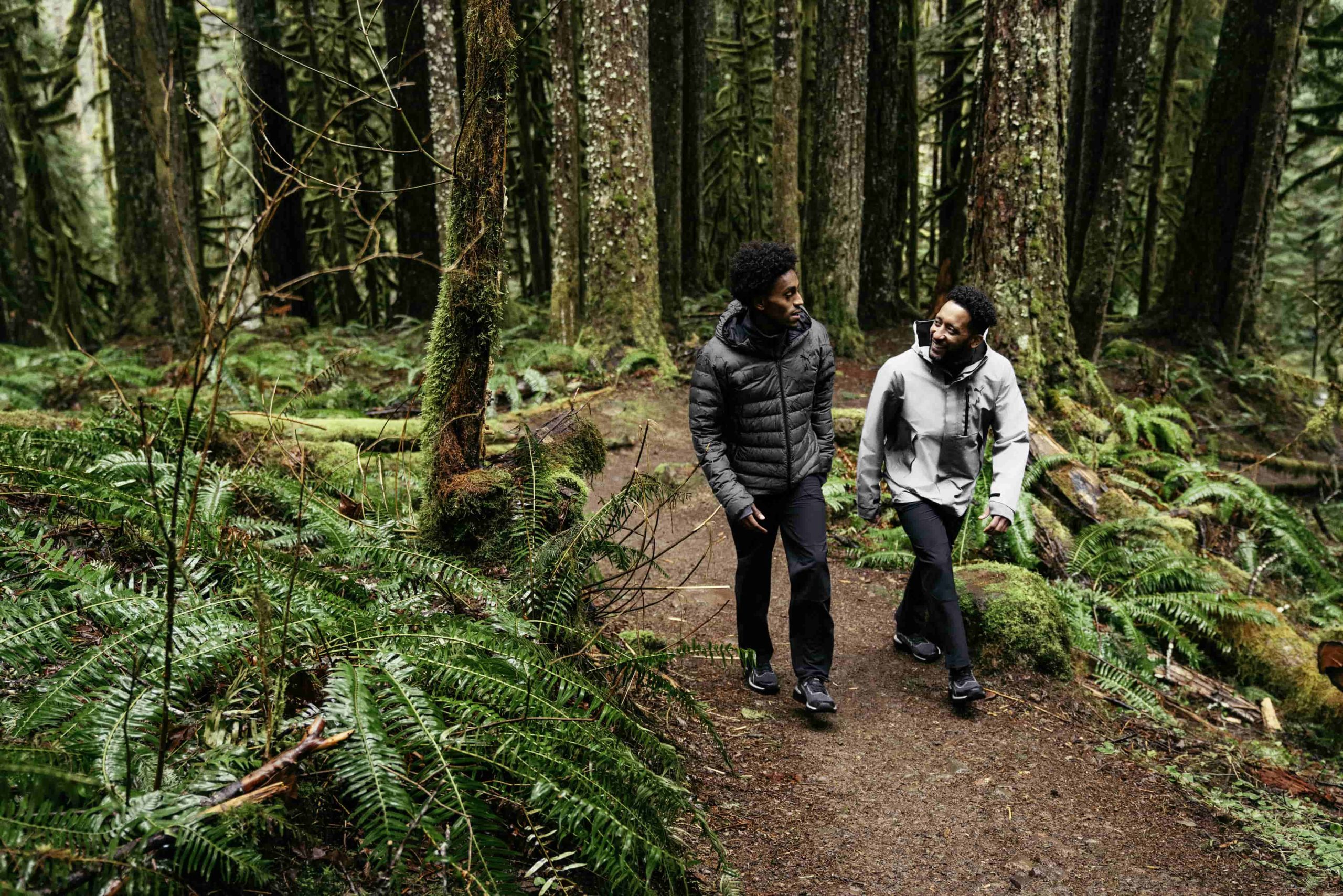 Deux hommes en tenue de trail PUMA marchent en forêt Deux hommes en tenue de trail PUMA marchent en forêt