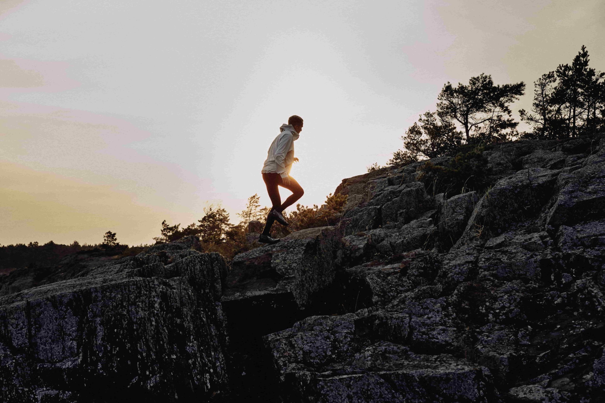 Un homme en tenue de trail PUMA court sur des rochers