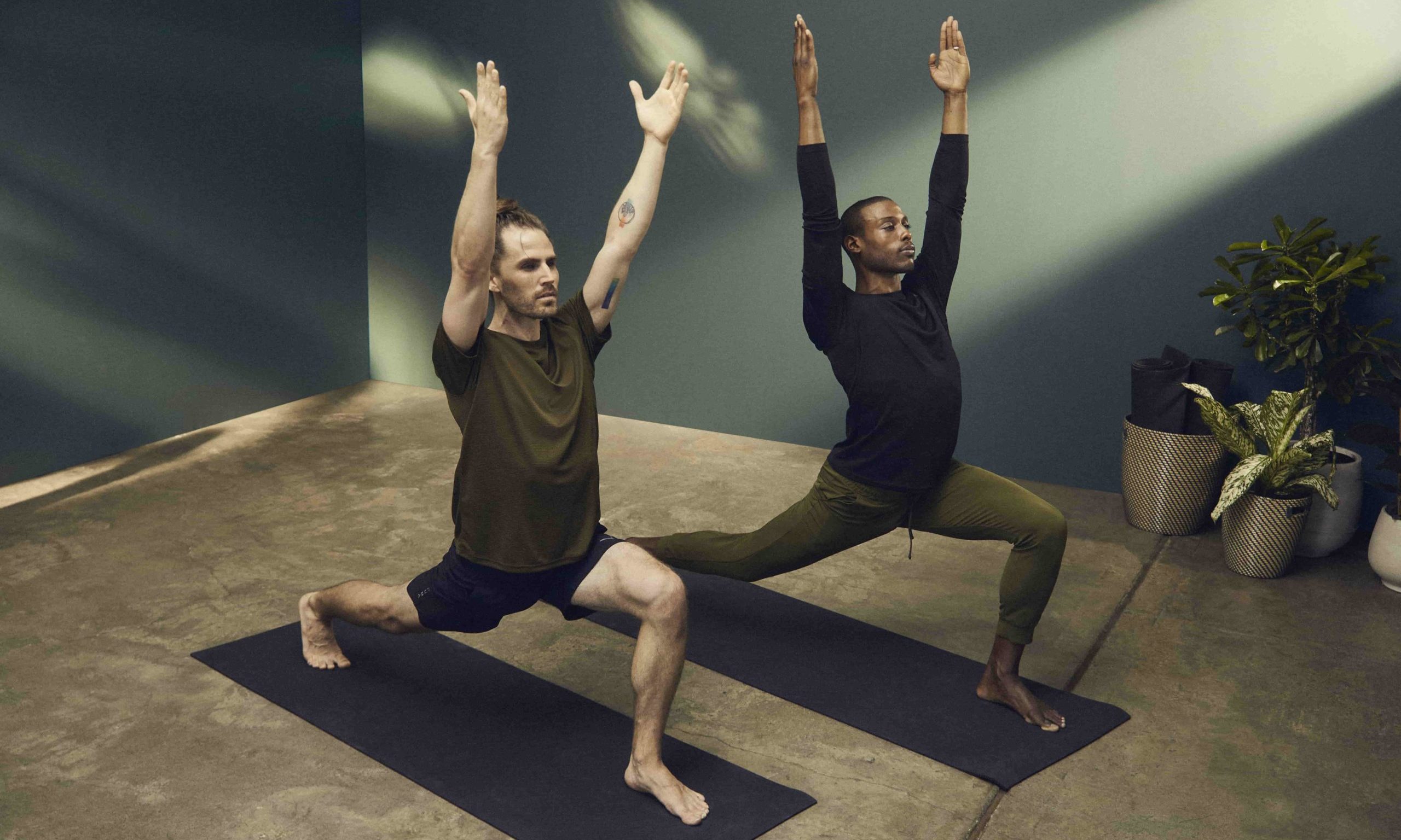 Zwei Männer in schwarz-dunkelgrüne PUMA Yoga Kleidung bei High Lunch Yoga Pose im Yoga Studio
