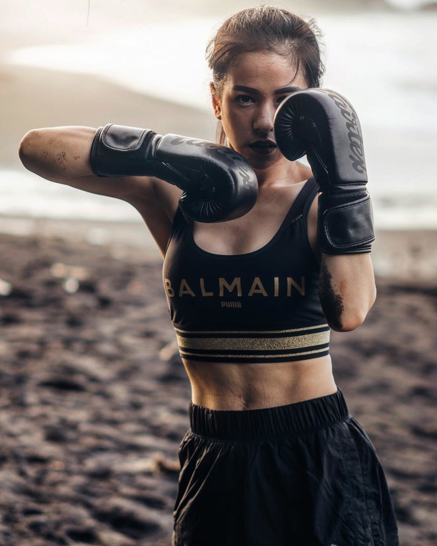 Boxerin in kurzer schwarzer Hose und Balmain x PUMA Sport-BH mit schwarten Boxhandschuhen
