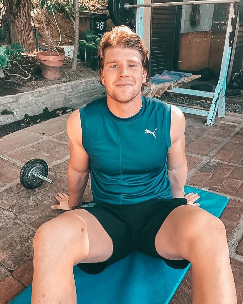 Evan Roos porte une tenue de sport PUMA et est assis sur un tapis de yoga