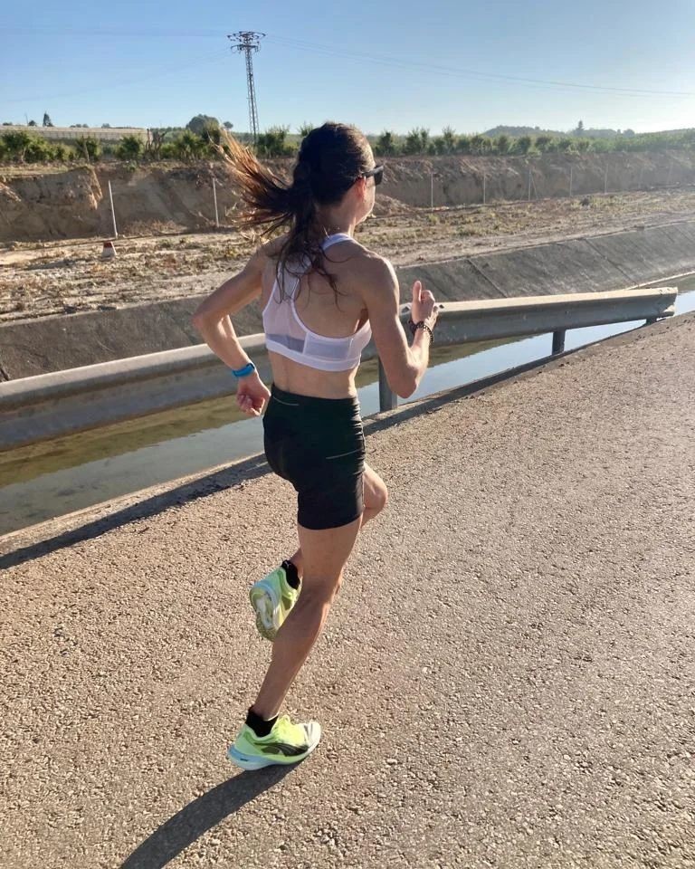Une femme en tenue de running PUMA fait son jogging en rue le long d’un canal
