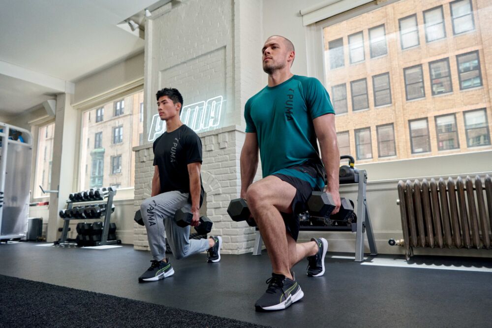 Deux hommes habillés de vêtements de fitness PUMA font des exercices avec haltères