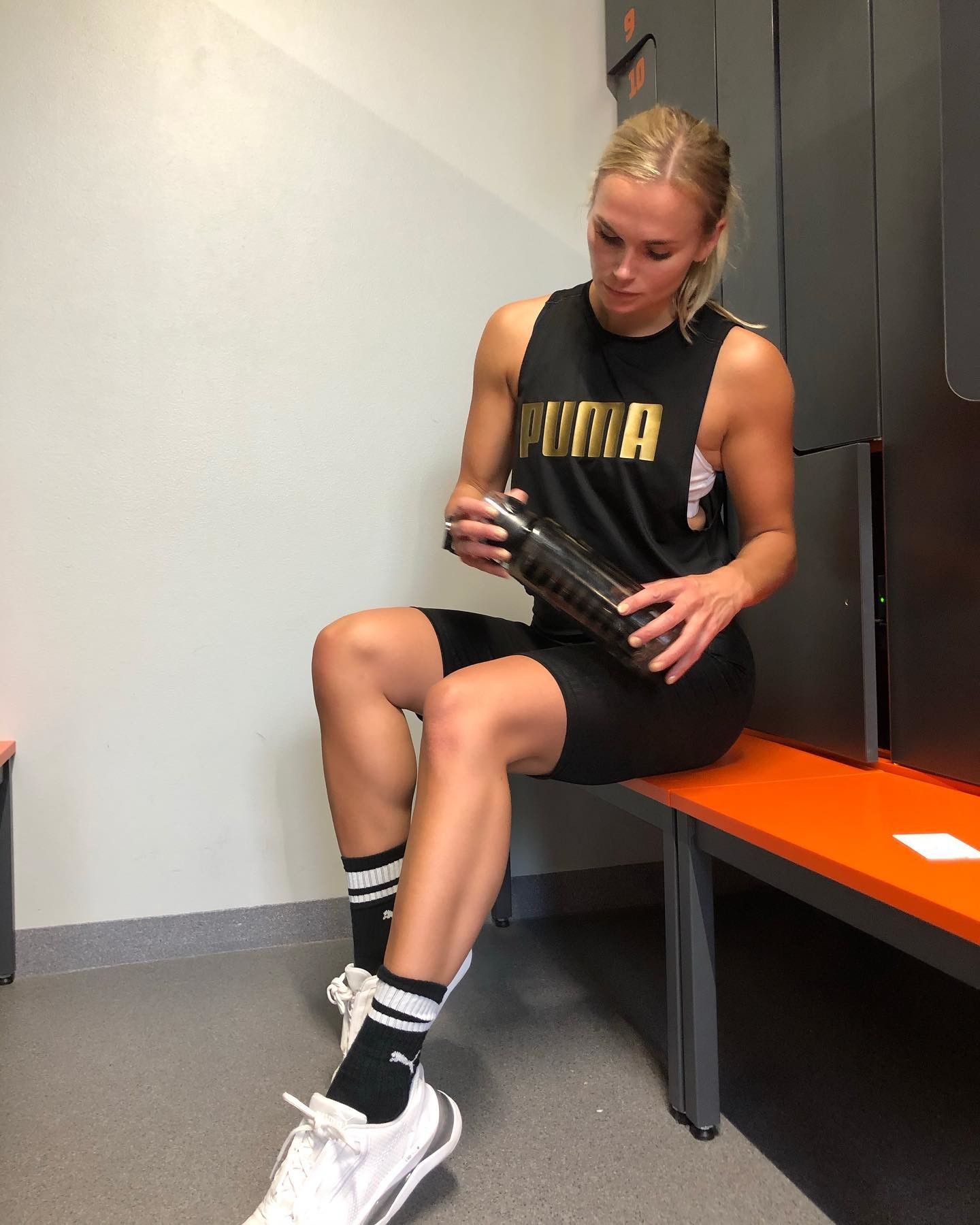 Sara Nikulainen porte des vêtements PUMA et est assise sur un banc de vestiaire